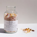 Revive Botanical Bath Salts 500g in glass bottle, with some of the product next to the bottle.