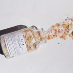 500gm Invigorate bath salts lid off with product ingredients spilling out of the glass bottle.