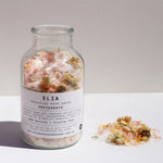 500gm Invigorate Botanical Bath Salts  with lid off and some of the product sitting next to the glass bottle.