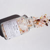 Revive Botanical Bath Salts 500g in glass bottle, with content spilling out of the bottle.