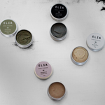 Image of  ELIA 15g deodorants with lids off, featuring Conscious Bicarb Free (Green), Activated Charcoal Deodorant (black), Pure Deodorant (white), Abundance Bicarb Free (Pink).